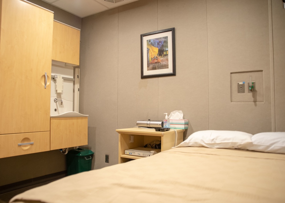 An empty sleep-study room with a bed, cabinets and equipment on a bedside table.